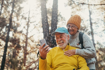 Portrait of young man using mobile phone while sitting in forest