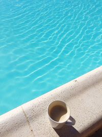 High angle view of coffee cup by swimming pool
