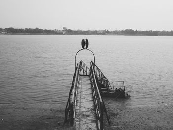 Boy on riverbank against clear sky