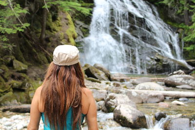 Rear view of woman standing against waterfall