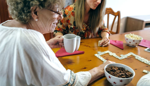 Midsection of woman holding coffee cup on table at home