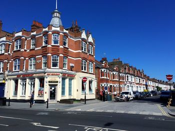 Road by buildings against sky in city