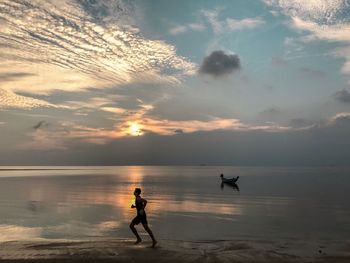 Silhouette woman on beach against sky during sunset