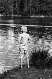 Rear view full length of boy fishing at lakeshore