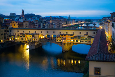 Illuminated bridge over river in city