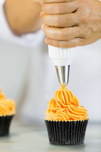 Close-up of chef icing cupcakes