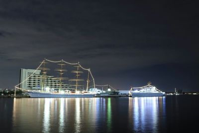Reflection of illuminated ships in calm sea at night