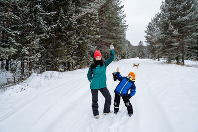 Mother and son enjoying on snow covered land during winter