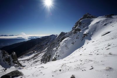 Scenic view of snowcapped mountains against sky on sunny day