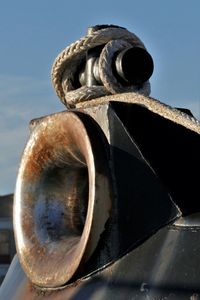 Low angle view of rusty wheel against sky