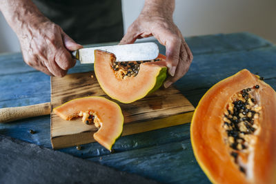 Hands of senior man cutting papaya