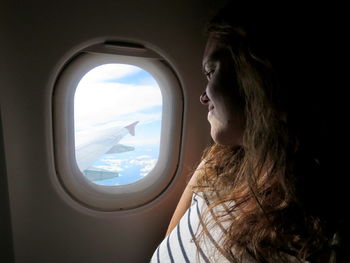 Close-up of young woman looking through airplane window