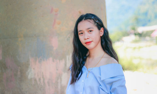 Portrait of beautiful woman standing against wall