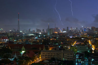 Illuminated cityscape against sky at night