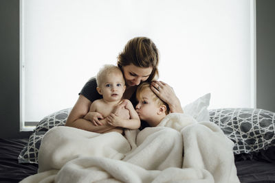 Mother with sons sitting on bed at home