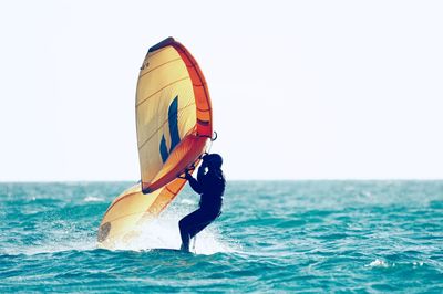 Man swimming in sea against clear sky