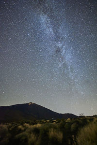 Low angle view of silhouette mountain against sky at night