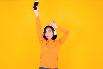 Woman standing against yellow wall