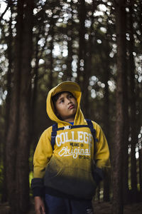 Full length of boy standing on tree trunk in forest
