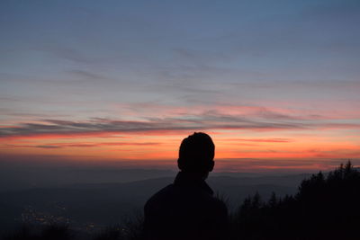 Silhouette man standing against orange sky during sunset