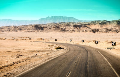 Road passing through landscape against blue sky