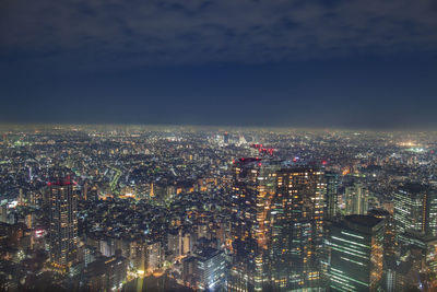 Illuminated buildings in city against sky at night