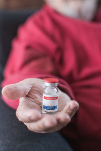 Coronavirus vaccine vial in elderly person's hand