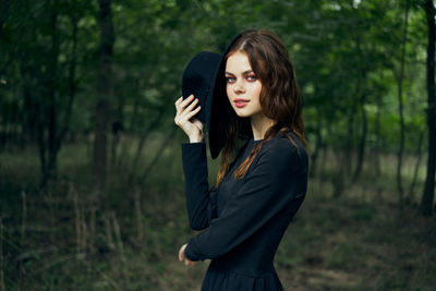 Young woman standing against trees