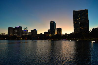 Sea by illuminated city buildings against sky