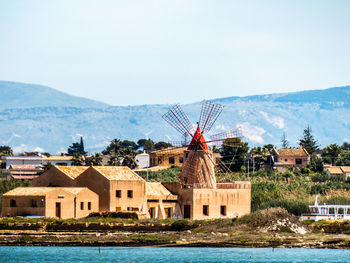 Houses by lake and buildings against sky