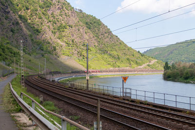 Railroad tracks by mountain against sky