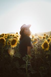 Portrait of woman standing by sunflower plants against sky