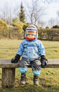 Full length of baby sitting wooden bench at park during winter