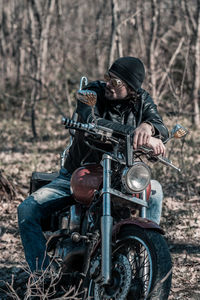 Full length of mid adult man sitting on motorcycle in forest