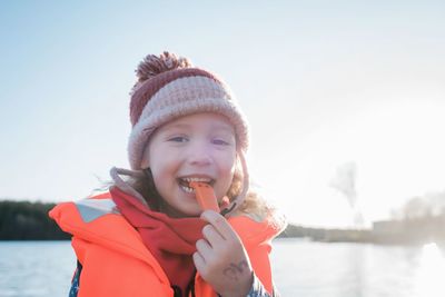 Portrait of a young girl with a life jacket on blowing a whistle