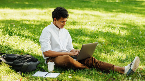 Young man using mobile phone in field