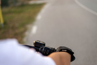 Cropped hand of man in gloves riding motorcycle on road