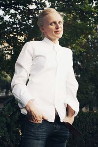 Portrait of woman standing on grass against trees