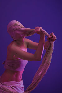 Midsection of woman dancing against blue background
