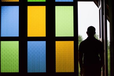 Rear view of man looking through window