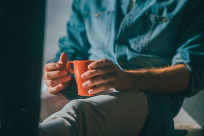 Midsection of man holding coffee cup