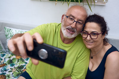 Portrait of smiling man photographing woman using mobile phone