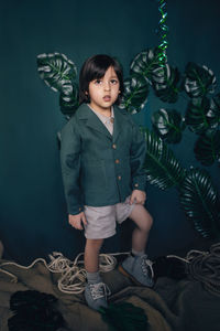 Boy child traveler in linen clothes green jacket stands in the studio