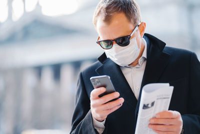 Businessman using smart phone while standing in city