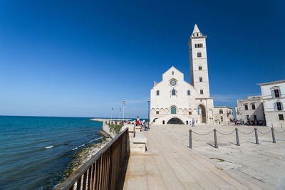 View of building by sea against clear blue sky