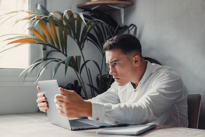 Side view of young man using laptop at home