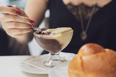 Woman with red nails eating sicilian granita at bar in the summer. brioche blurred in the front.