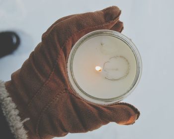 Close-up of cropped hand holding tea light candle during winter