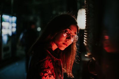 Portrait of young woman looking away at night