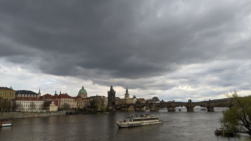 Buildings by river against cloudy sky